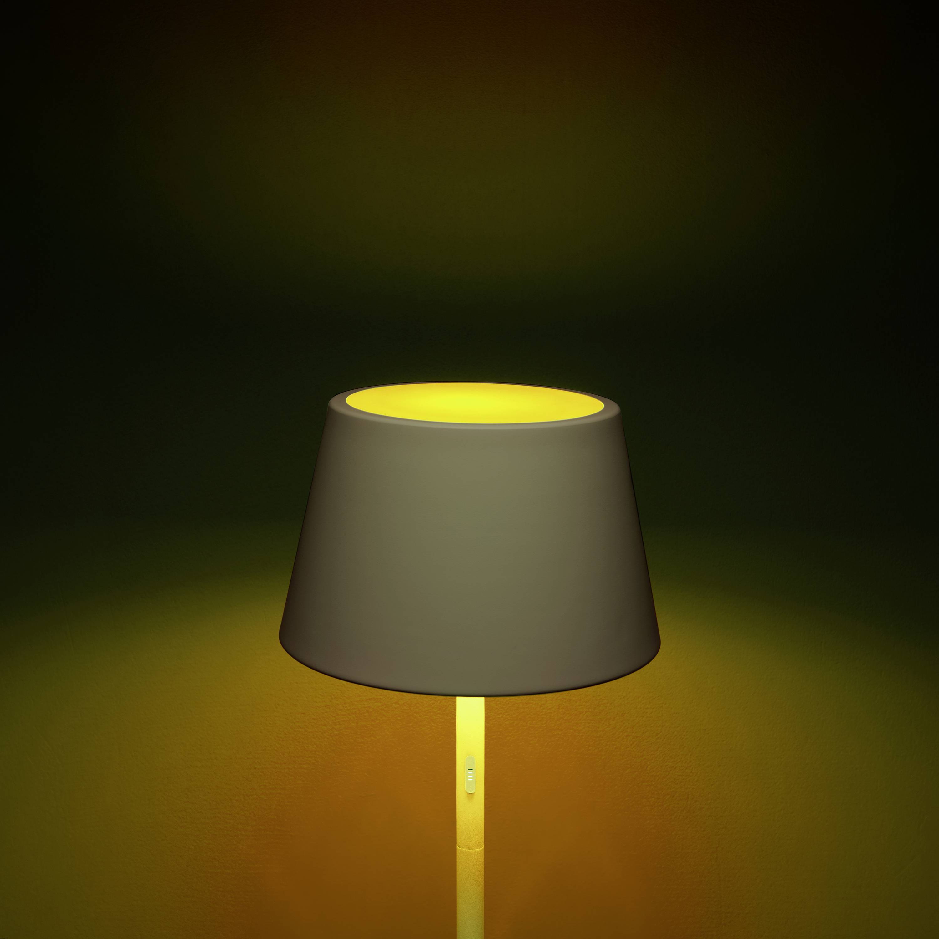Eine eingeschaltete Tischlampe mit einem schwarzen Lampenschirm beleuchtet einen dunkelgelben Hintergrund, schafft eine warme Atmosphäre.