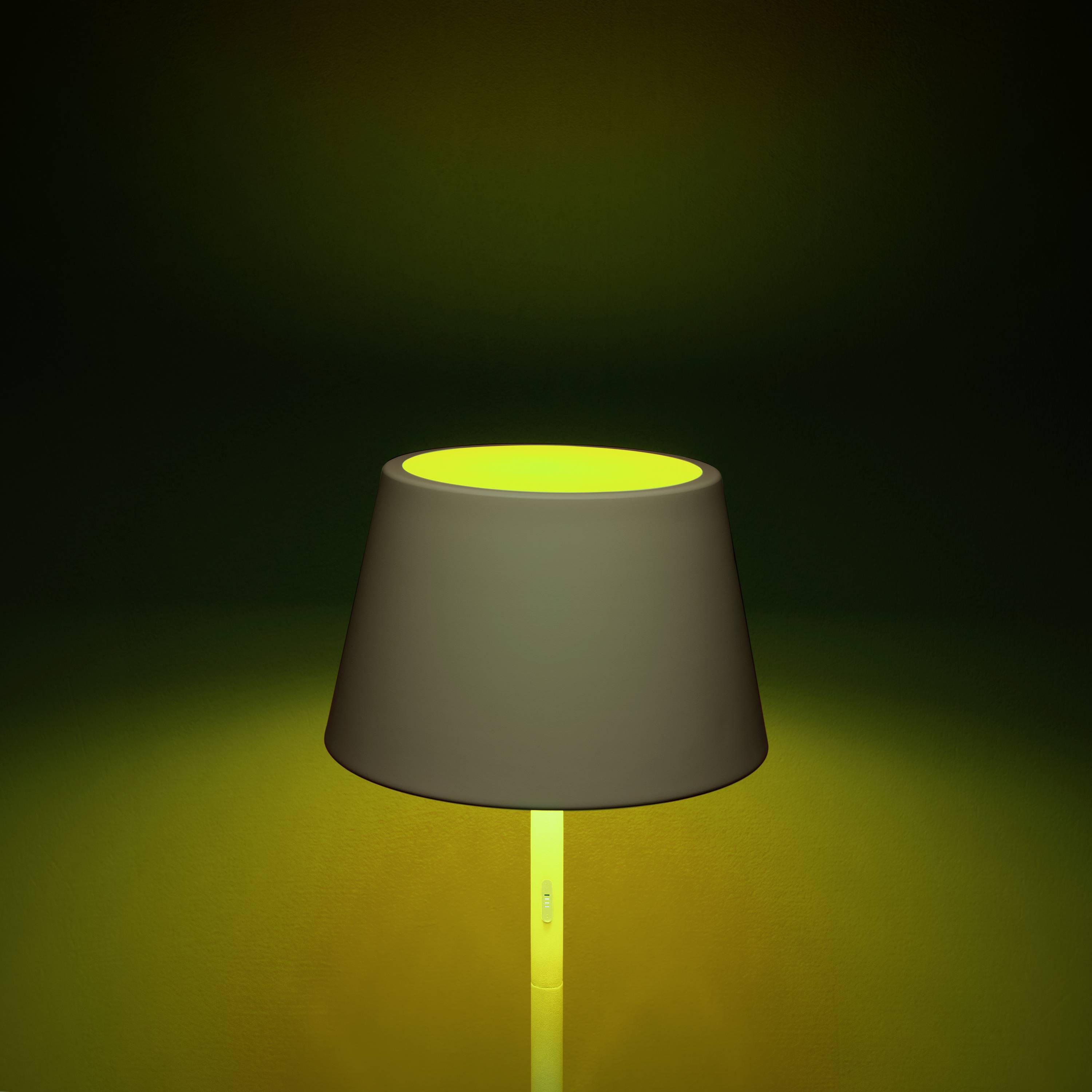 Eine Tischlampe mit grünem Schimmer um den Schirm, beleuchtet von innen, steht vor einem dunklen Hintergrund.
