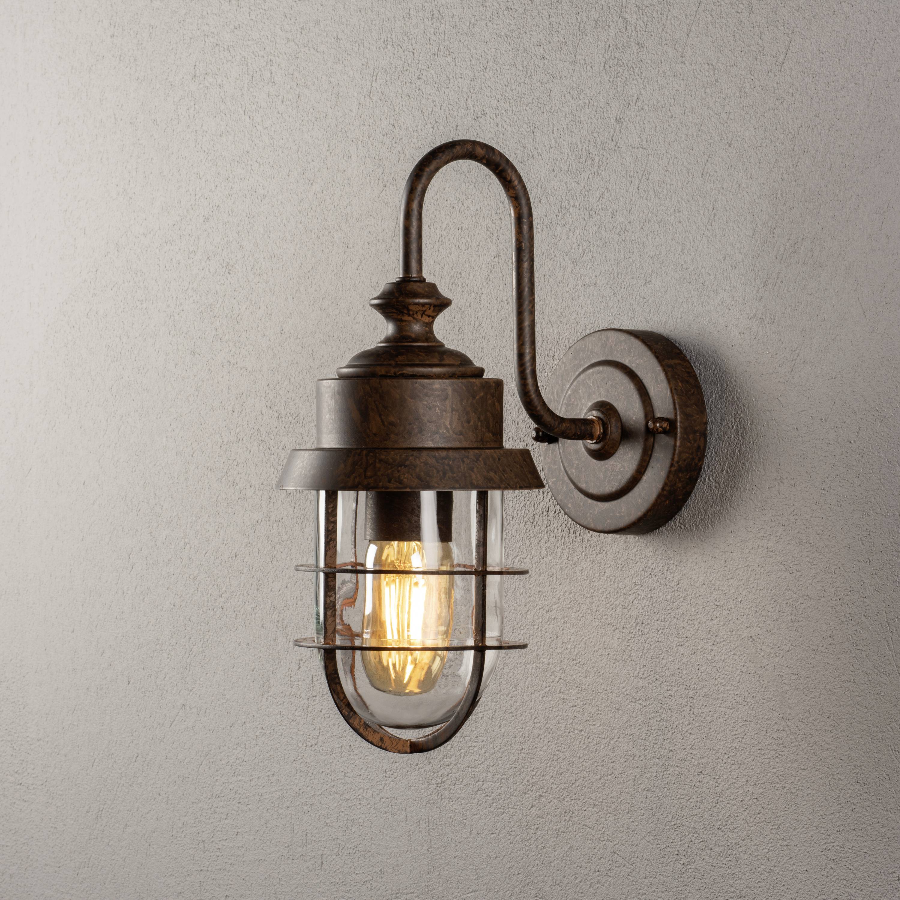 Rustikale Wandleuchte aus Metall mit rundem Glasschirm, die warmes Licht ausstrahlt. Befestigt an einer Wand mit sanfter Textur.