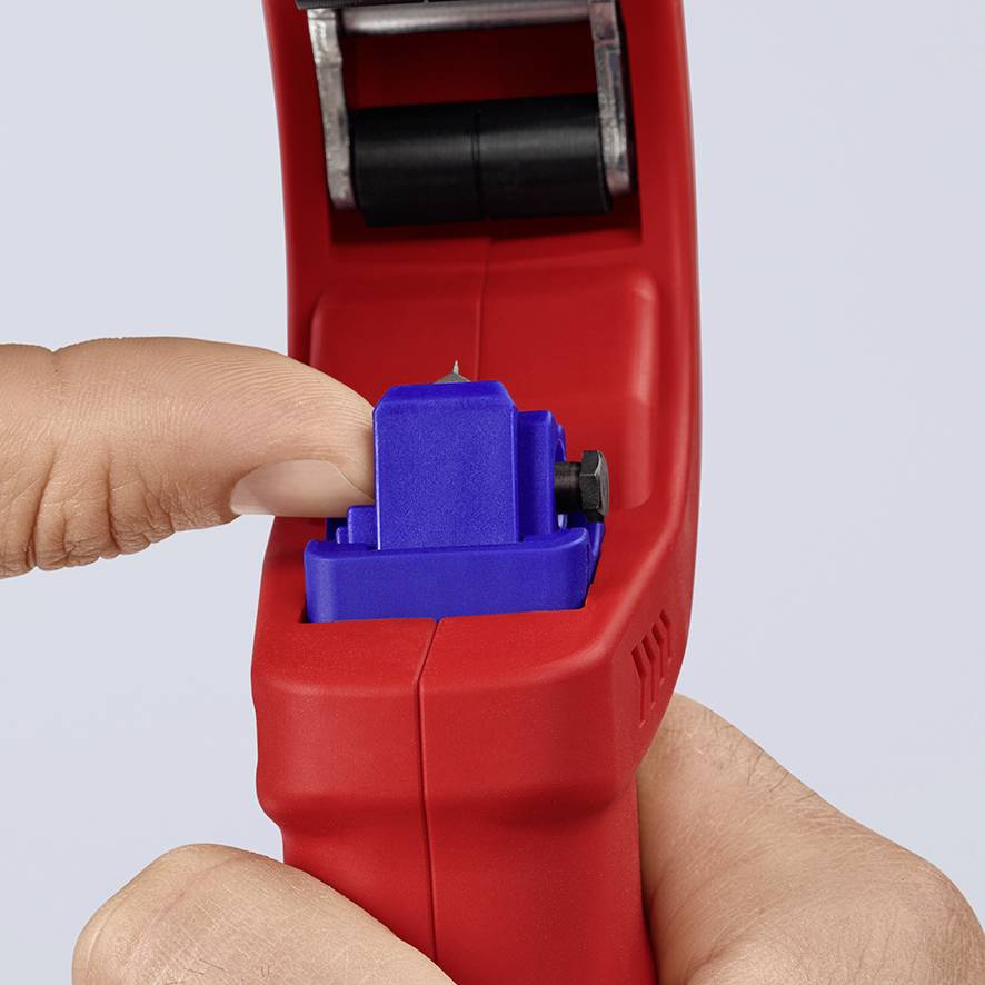 Eine Hand hält einen roten Etikettierer und betätigt den blauen Hebel, um ein Etikett zu drucken.