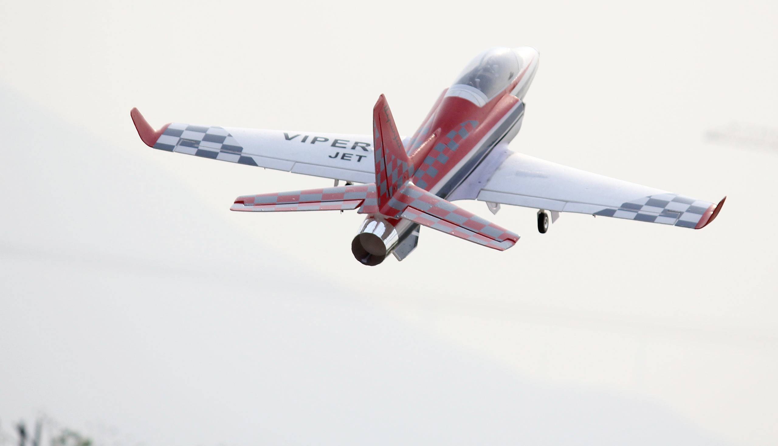 Ein Modellflugzeug in Rot und Weiß mit der Aufschrift 'Viper Jet' fliegt in der Luft.