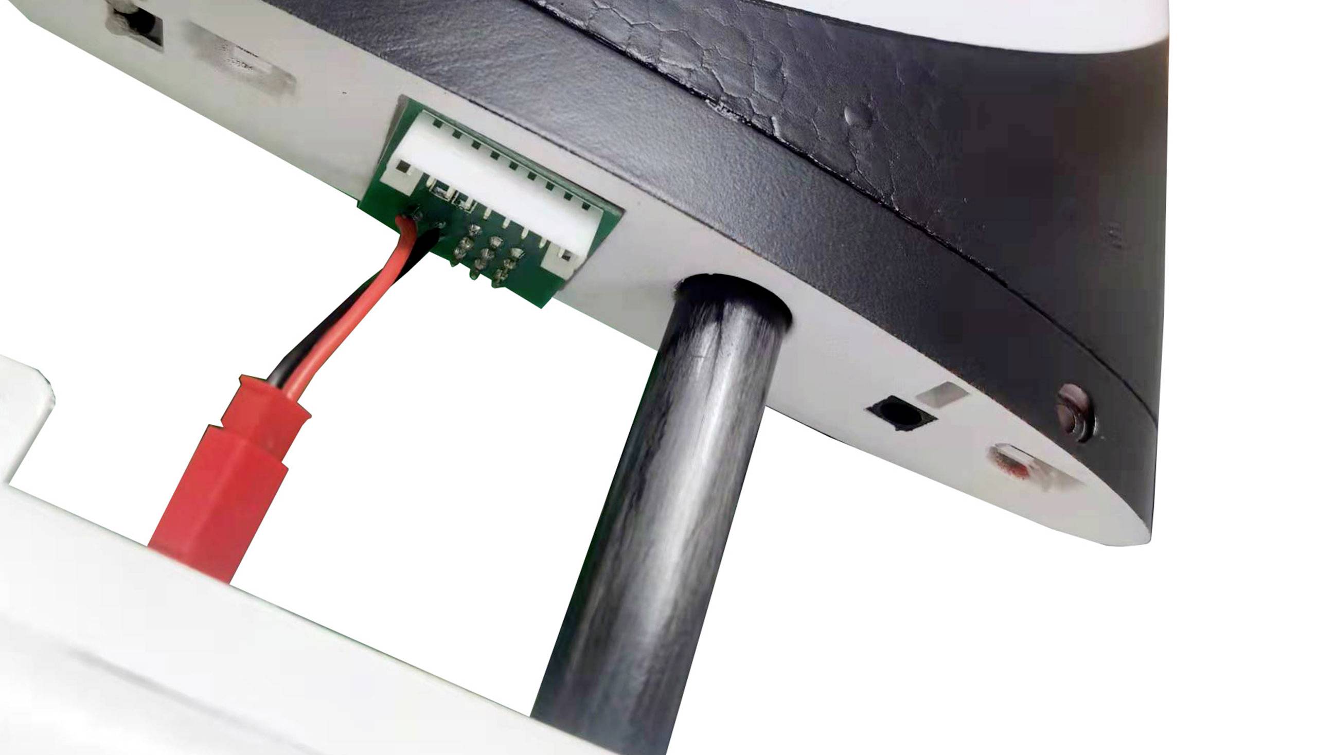 'Unterseite eines elektronischen Geräts mit schwarzem Gehäuse und sichtbarem Anschlusskabel.'