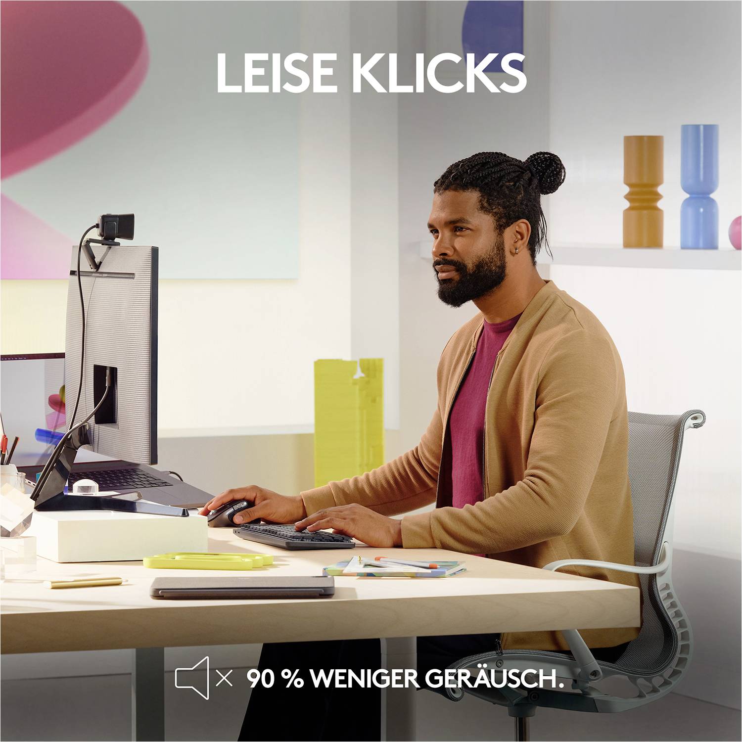 Ein Mann arbeitet an einem Computer mit der Aufschrift 'Leise Klicks' und '90 % weniger Geräusch'.