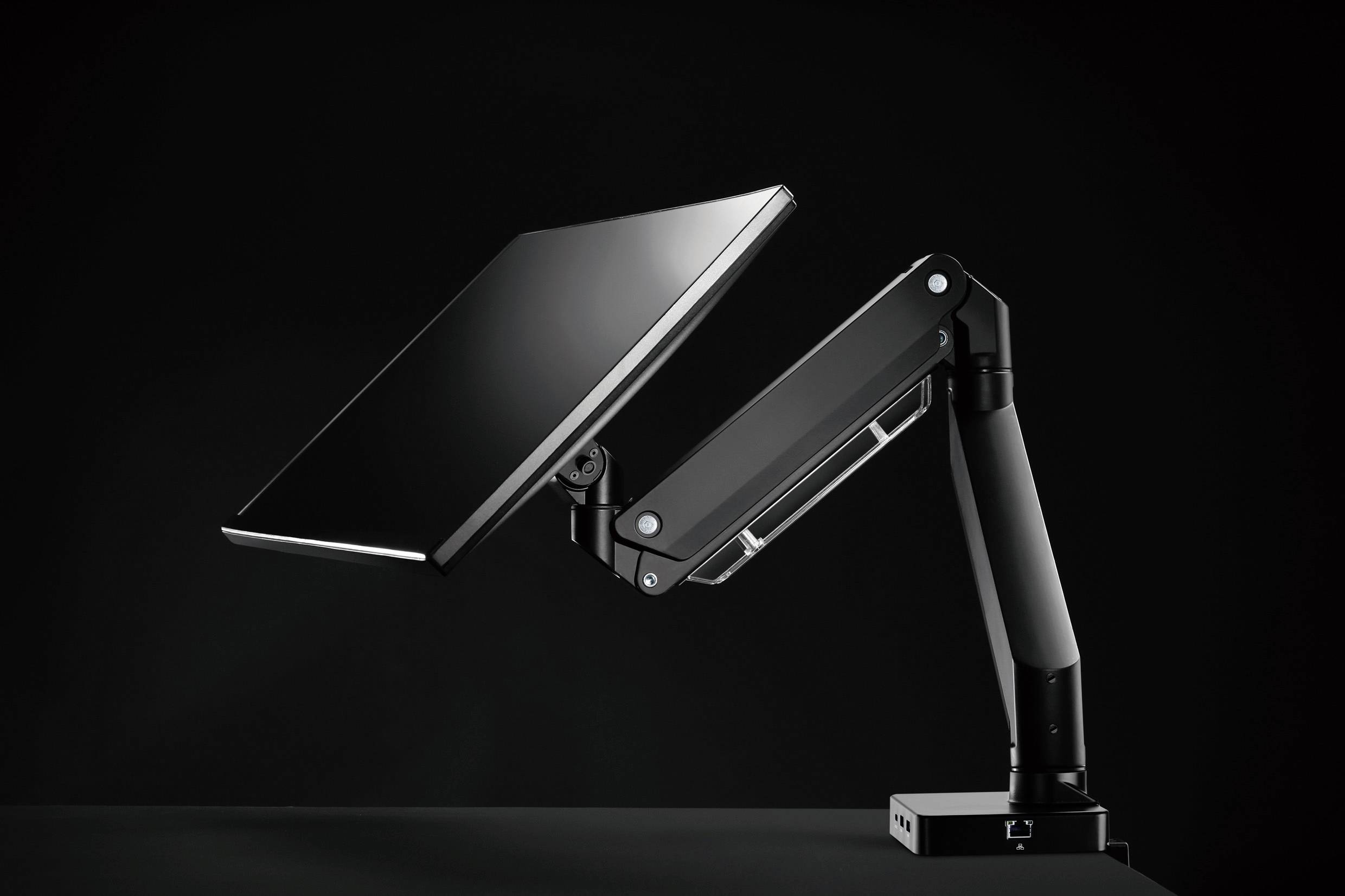 Schwenkbarer Monitorarm auf einem Tisch. Der Arm hält einen flachen Bildschirm und ermöglicht flexible Positionierung und Einstellung.