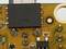 Nahaufnahme einer Leiterplatte mit elektronischen Bauteilen, einschließlich eines großen schwarzen Mikrochips.