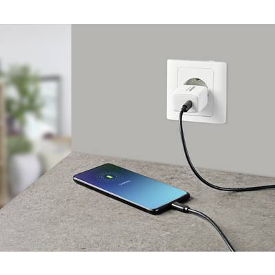 Ein Smartphone liegt auf einem Tisch und ist mit einem Kabel an eine Steckdose angeschlossen. Der Bildschirm zeigt 'Laden'.