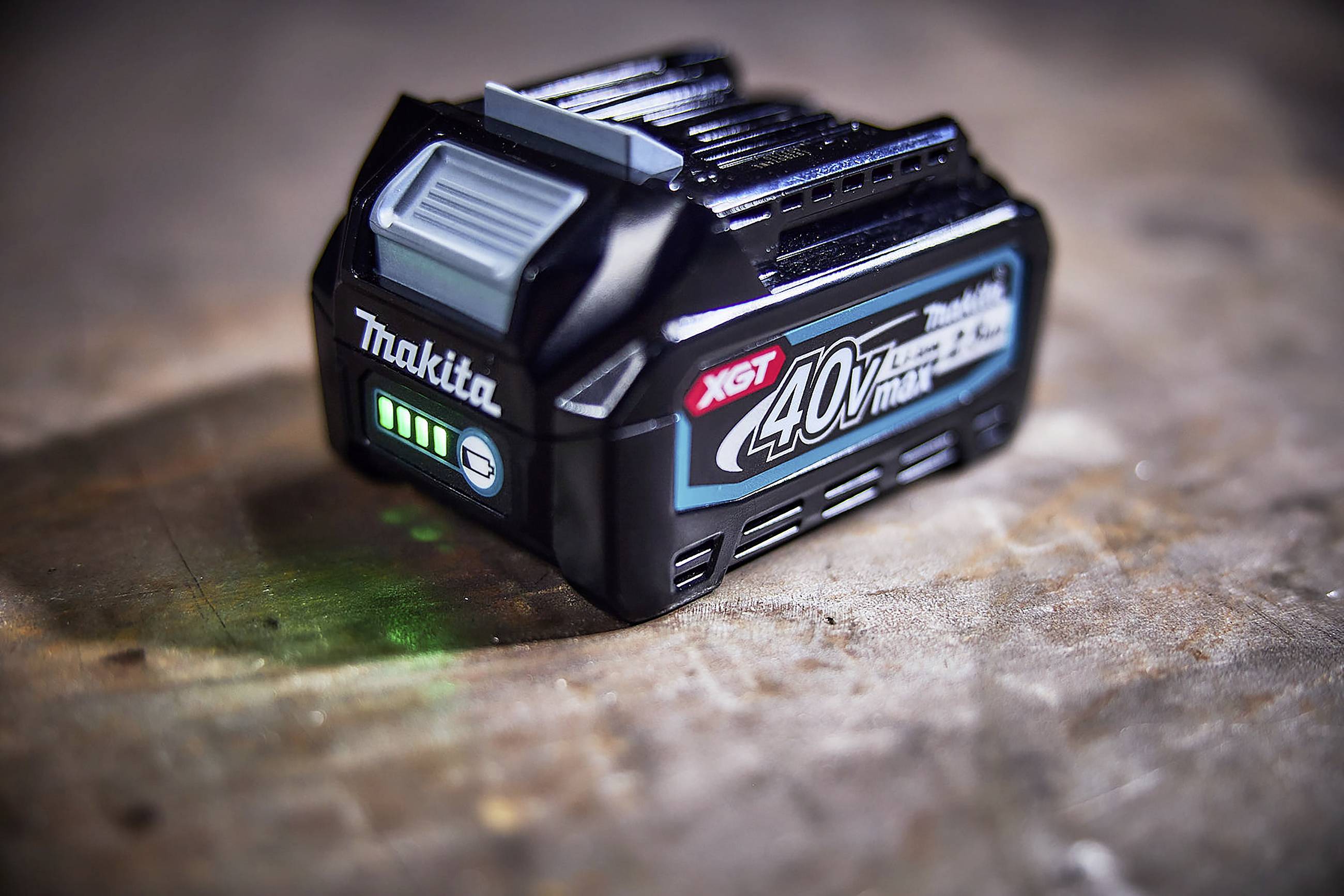 Makita 40V XGT-Akku mit LED-Anzeige auf Holztisch. Zeigt Ladezustand, geeignet für leistungsstarke Elektrowerkzeuge.
