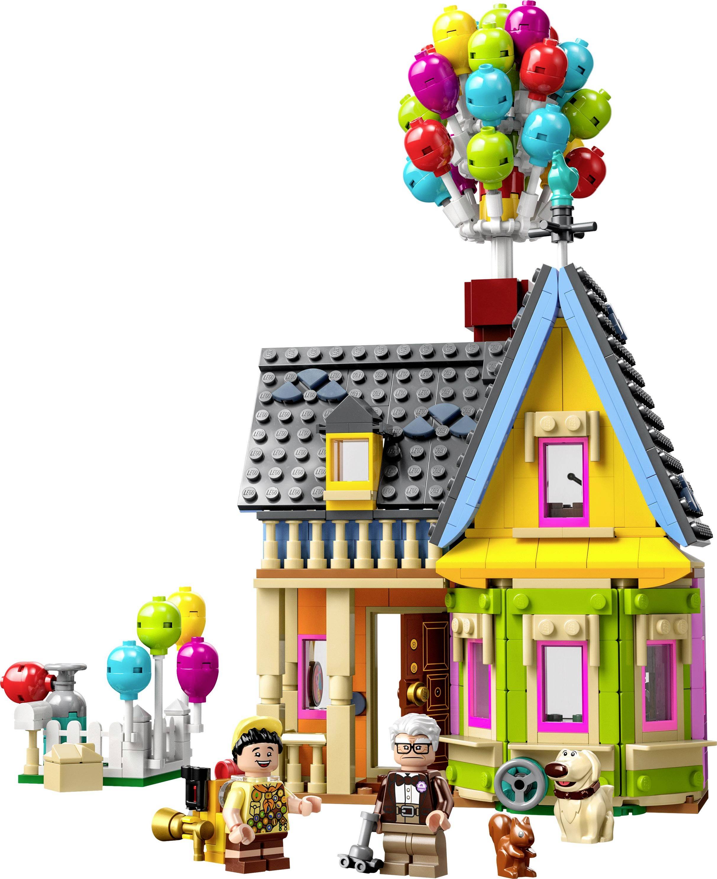 Ein buntes Spielzeughaus mit Luftballons auf dem Dach, begleitet von zwei Figuren und einem Hund, alles aus Bausteinen gefertigt.