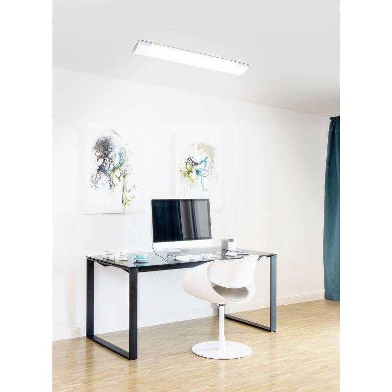 Ein moderner Schreibtisch mit Computer und Stuhl vor weißer Wand, zwei abstrakte Gemälde oberhalb, und ein helles Deckenlicht.