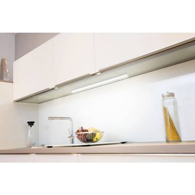 Schlicht gestaltete Küche mit weißem Schrank, beleuchtet durch eine Unterbauleuchte. Auf der Arbeitsplatte steht eine Obstschale und ein Glas mit Spaghetti.