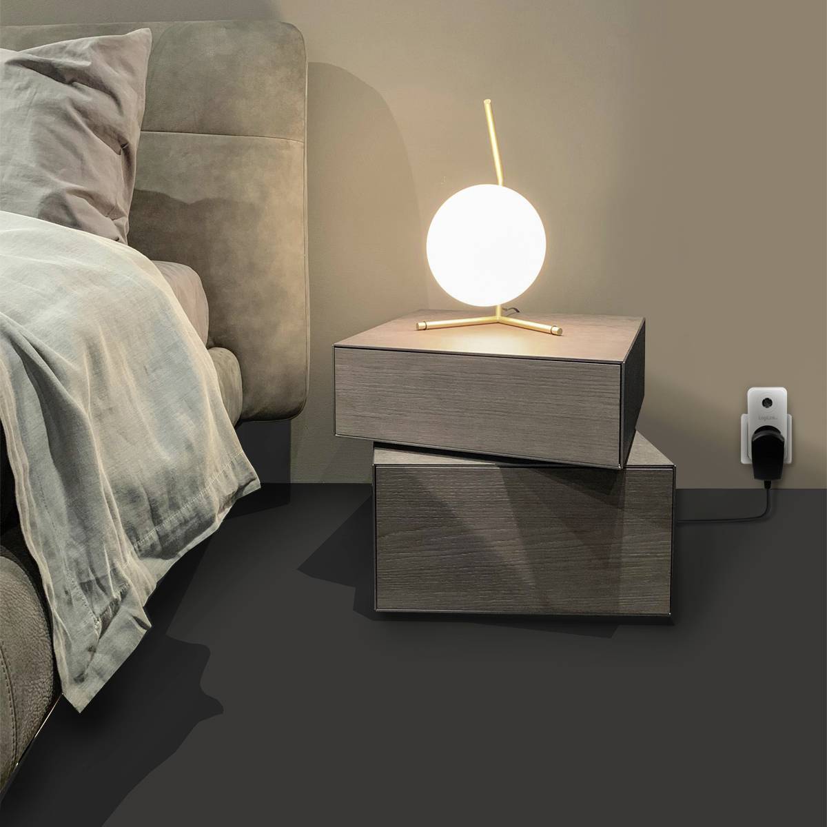 Ein Bett mit grauer Bettwäsche steht neben zwei übereinander gestapelten Nachttischen. Auf den Tischen steht eine moderne, kugelförmige Lampe.