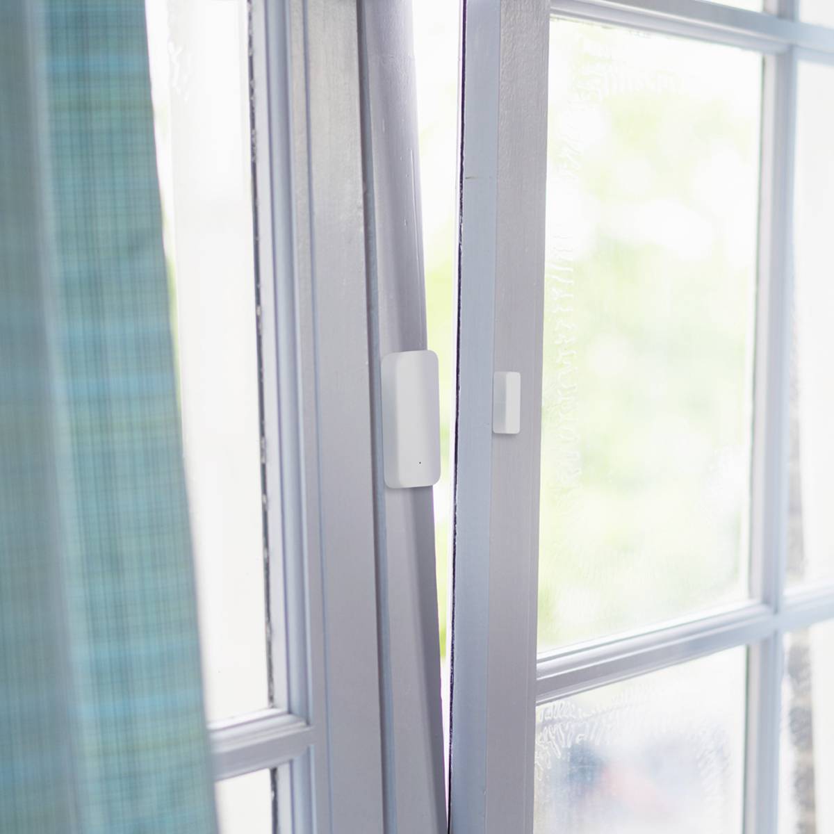 Ein geöffnetes Fenster mit weißen Rahmen und hellen Vorhängen an der Seite. Tageslicht strömt herein und erhellt den Raum.