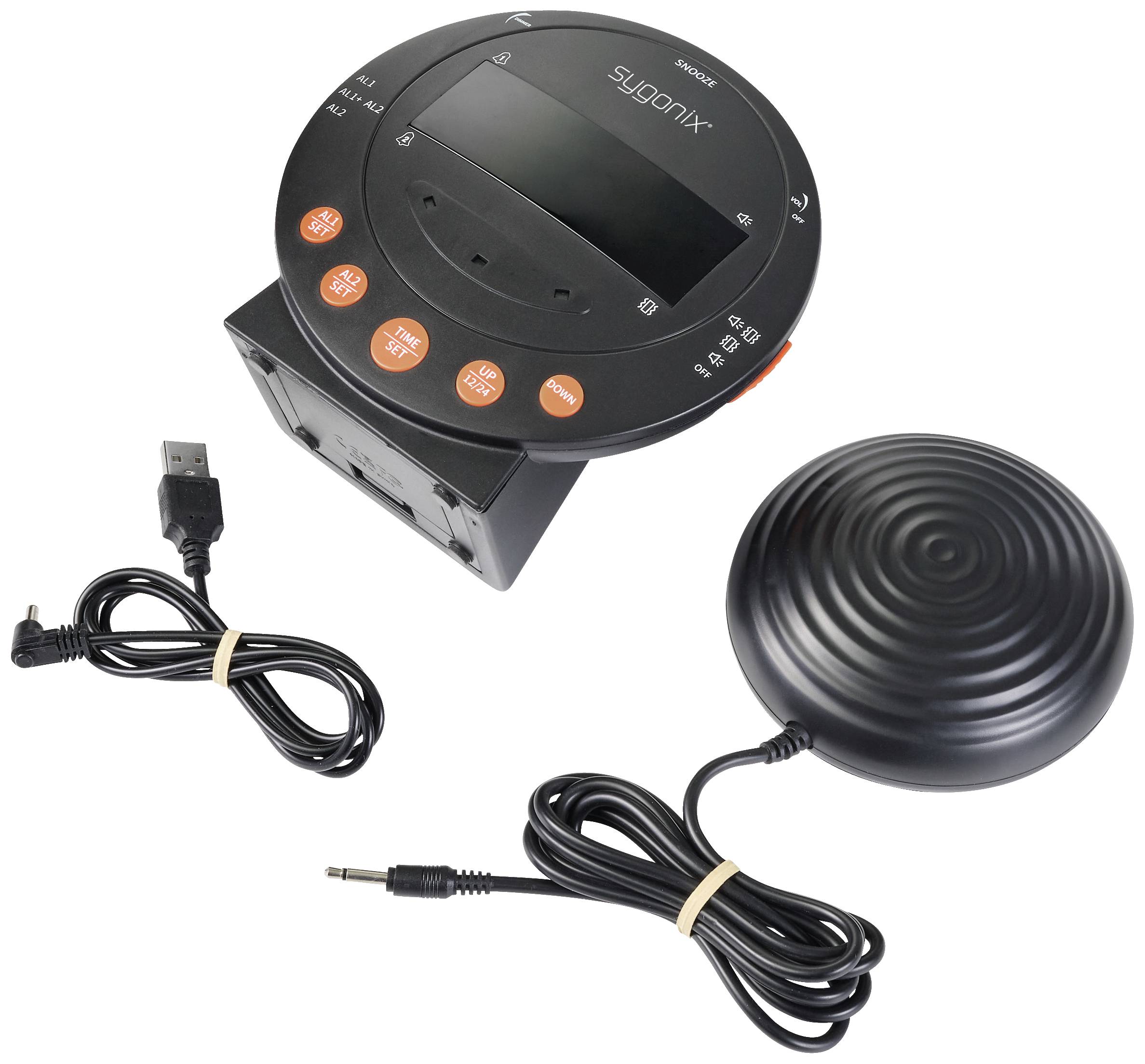 Ein Wecker mit USB-Anschluss, mehreren Tasten und einem großen Ziffernblatt. Neben dem Wecker sind Kabel und ein runder Lautsprecher abgebildet.