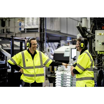 Zwei Männer in gelben Warnwesten stehen in einer Fabrikhalle und unterhalten sich. Beide tragen Gehörschutz mit Mikrofonen.