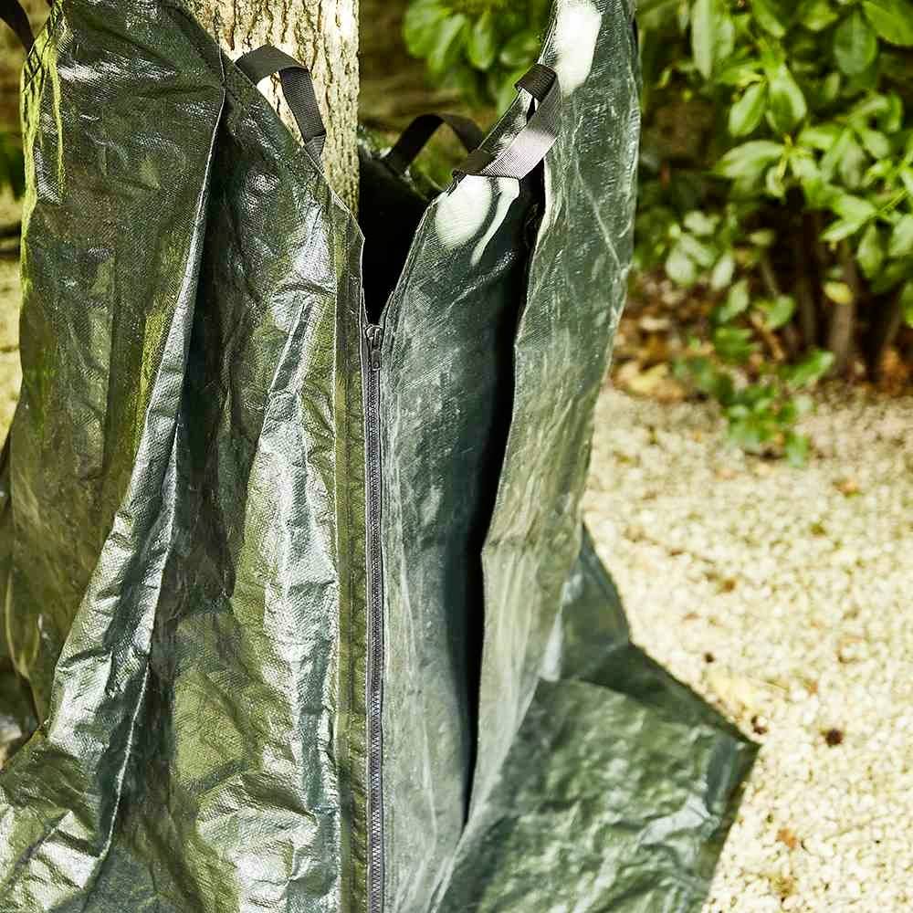 Ein Baum steht in einem offenen Zelt aus robustem, dunkelgrünem Material. Das Zelt ist an einem Baumstamm befestigt.