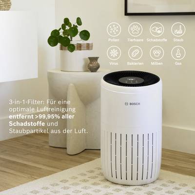 Ein weißer Bosch-Luftreiniger in einem Wohnzimmer. Text informiert über die Entfernung von 99,95% schädlicher Partikel aus der Luft.