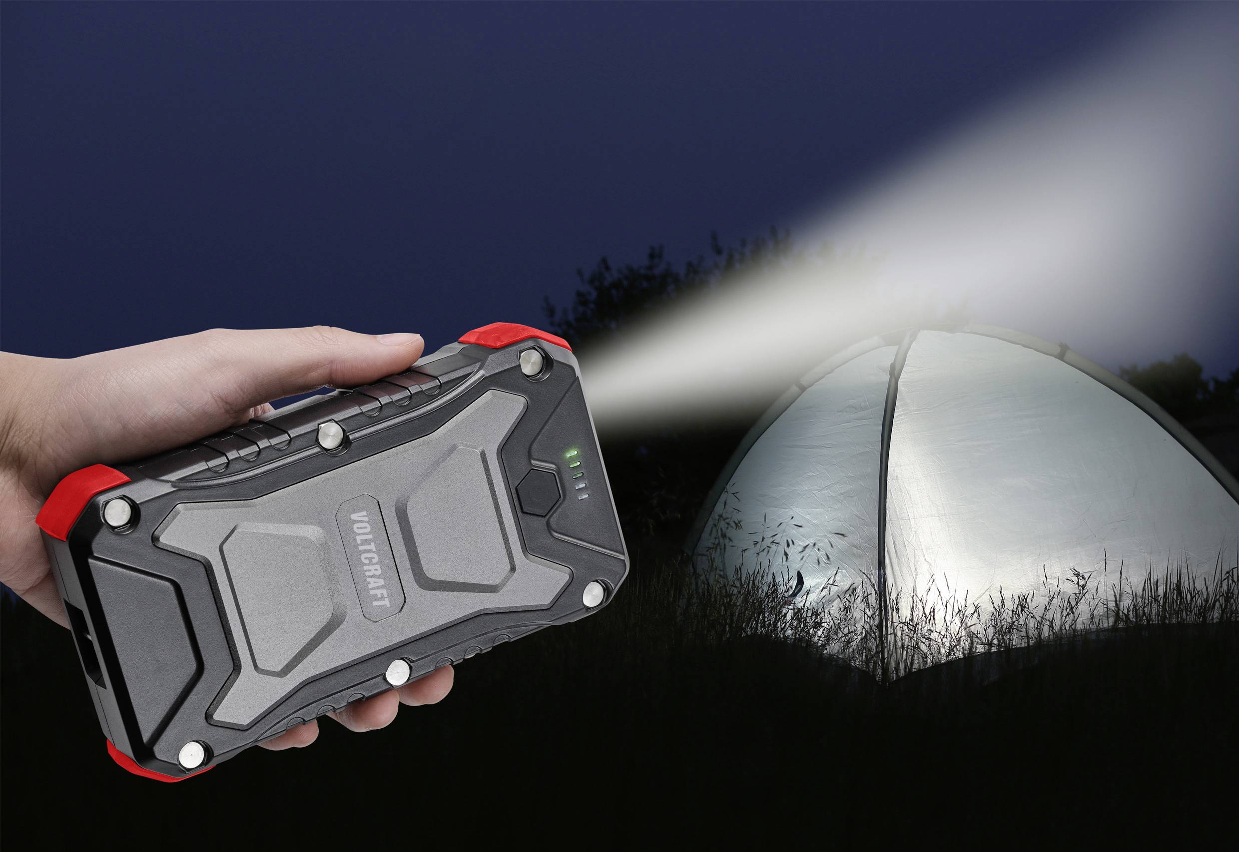 Ein Hand hält eine Taschenlampe, die auf ein beleuchtetes Zelt im Dunkeln strahlt. Der Hintergrund ist nächtlich.