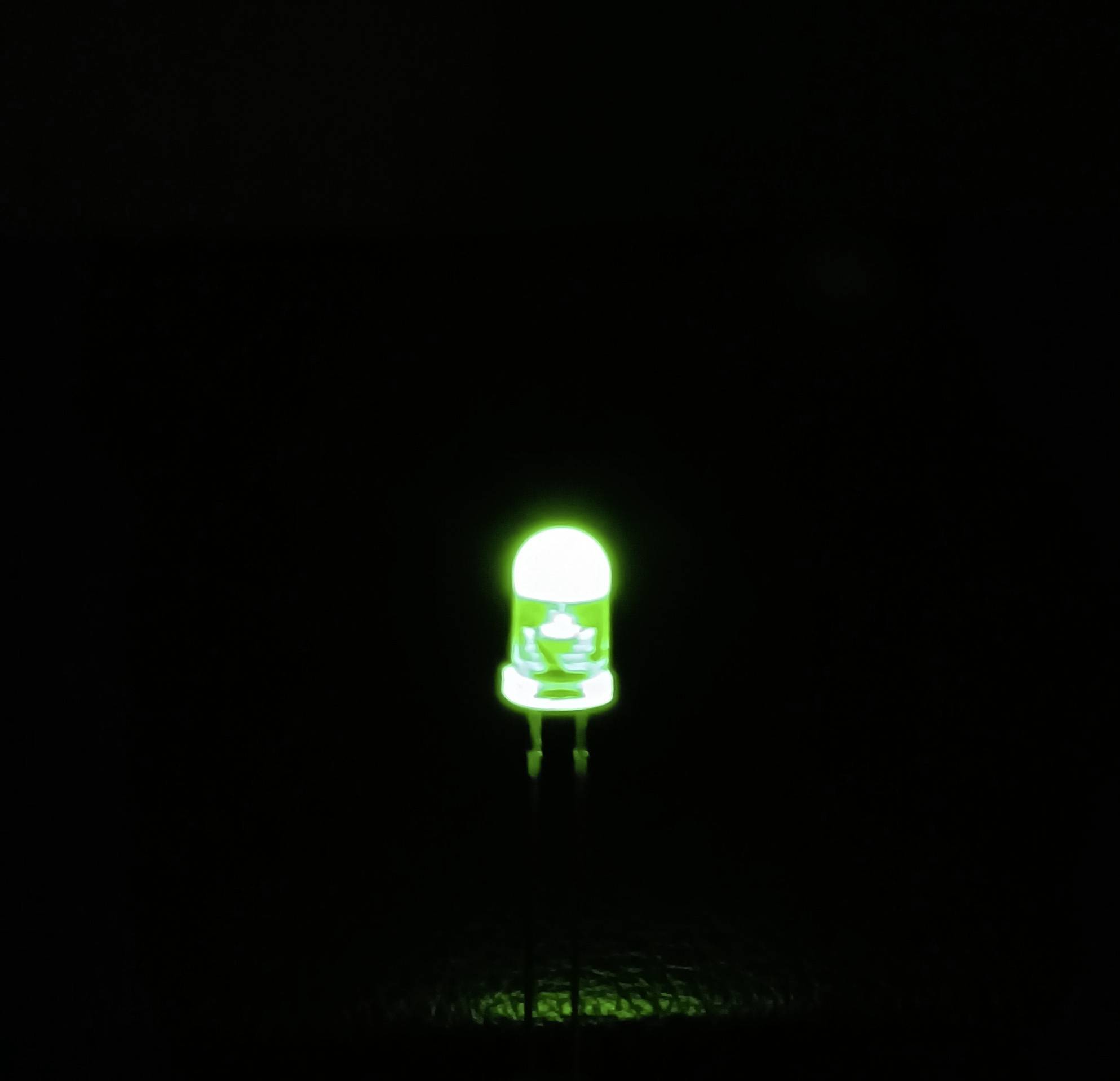 Eine leuchtende grüne LED auf dunklem Hintergrund.