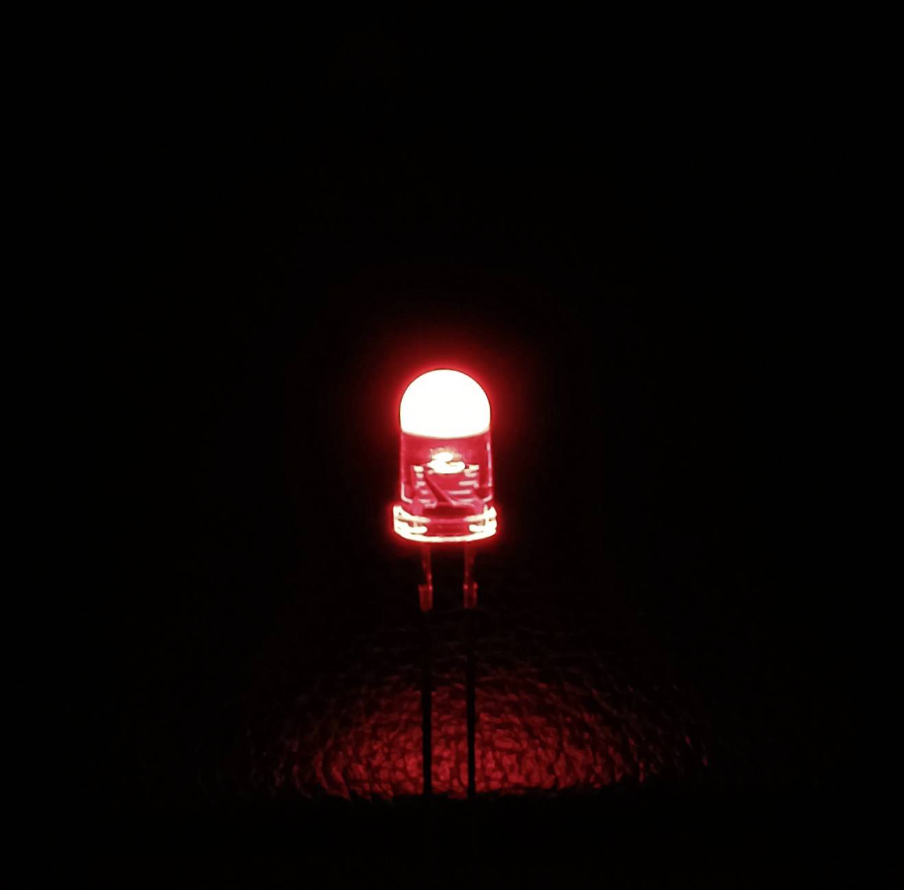 Eine leuchtende rote LED-Glühbirne vor einem schwarzen Hintergrund.
