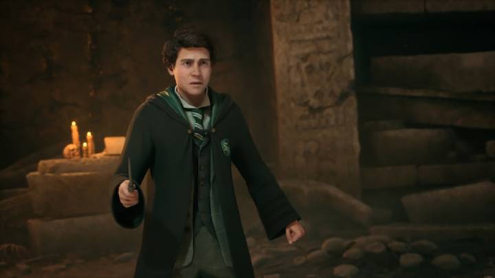 Ein junger Mann in einem Hogwarts-ähnlichen Umhang steht in einem dunklen, steinernen Raum mit Kerzen, hält einen Zauberstab und wirkt entschlossen.