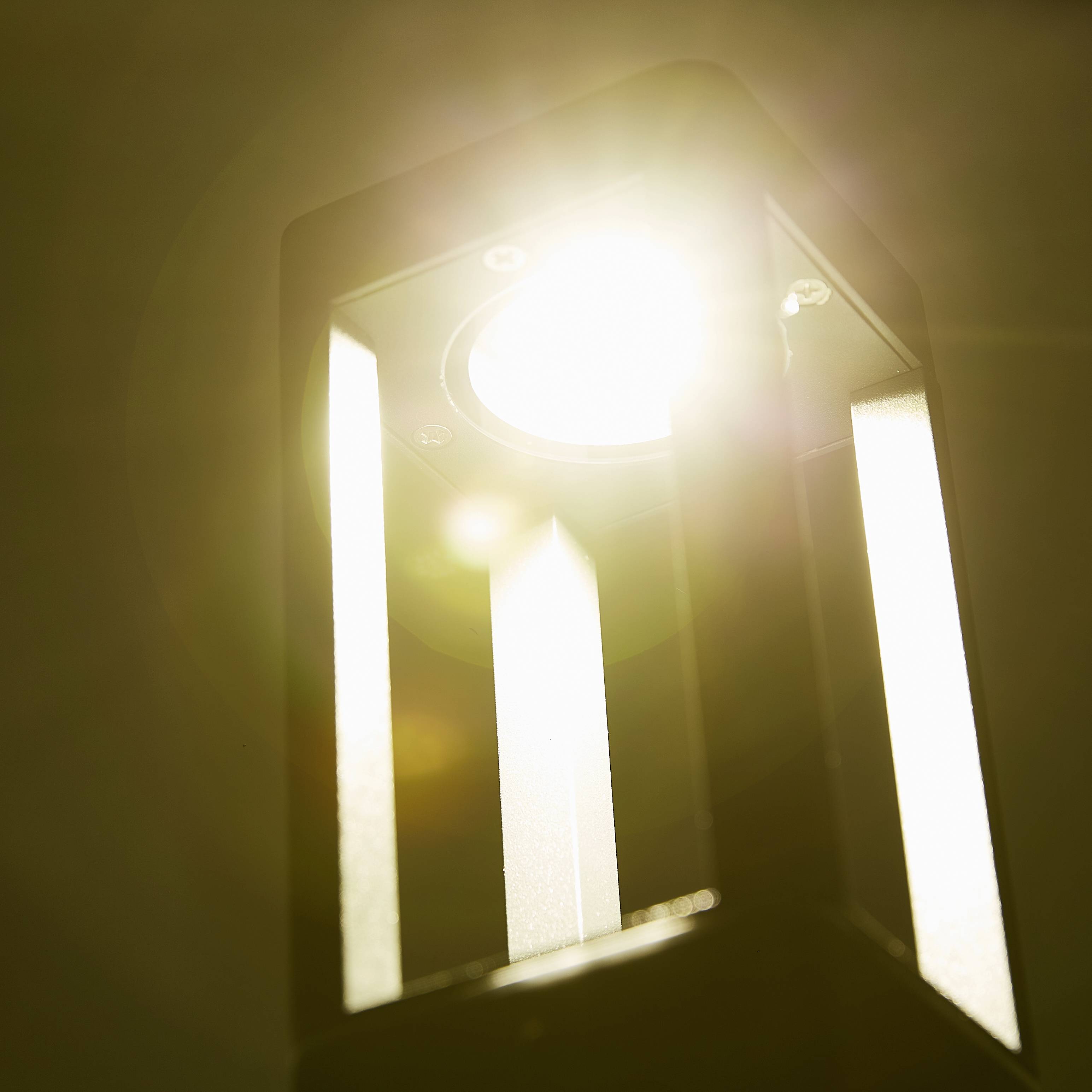 Eine helle Lampe, die direkt nach unten leuchtet, erzeugt starke Lichtstrahlen in einem dunklen Raum.