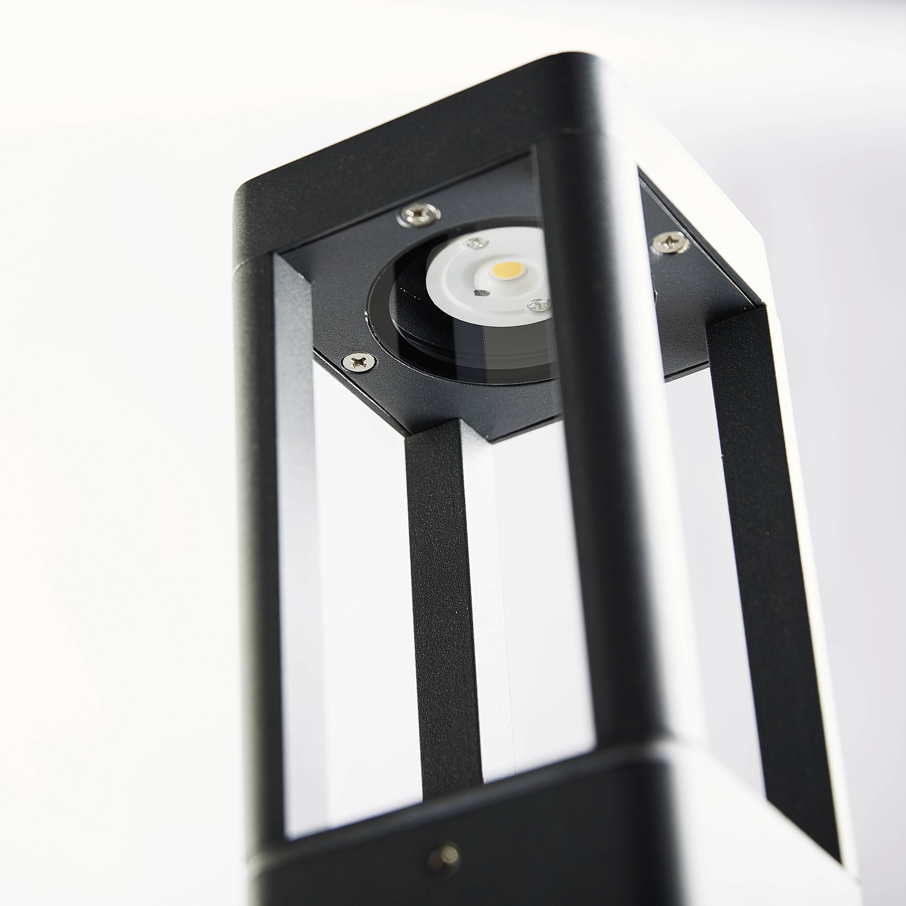 Ein rechteckiger LED-Strahler in Nahaufnahme, der an einer Wand montiert ist. Die silberne und schwarze Oberfläche reflektiert Licht.