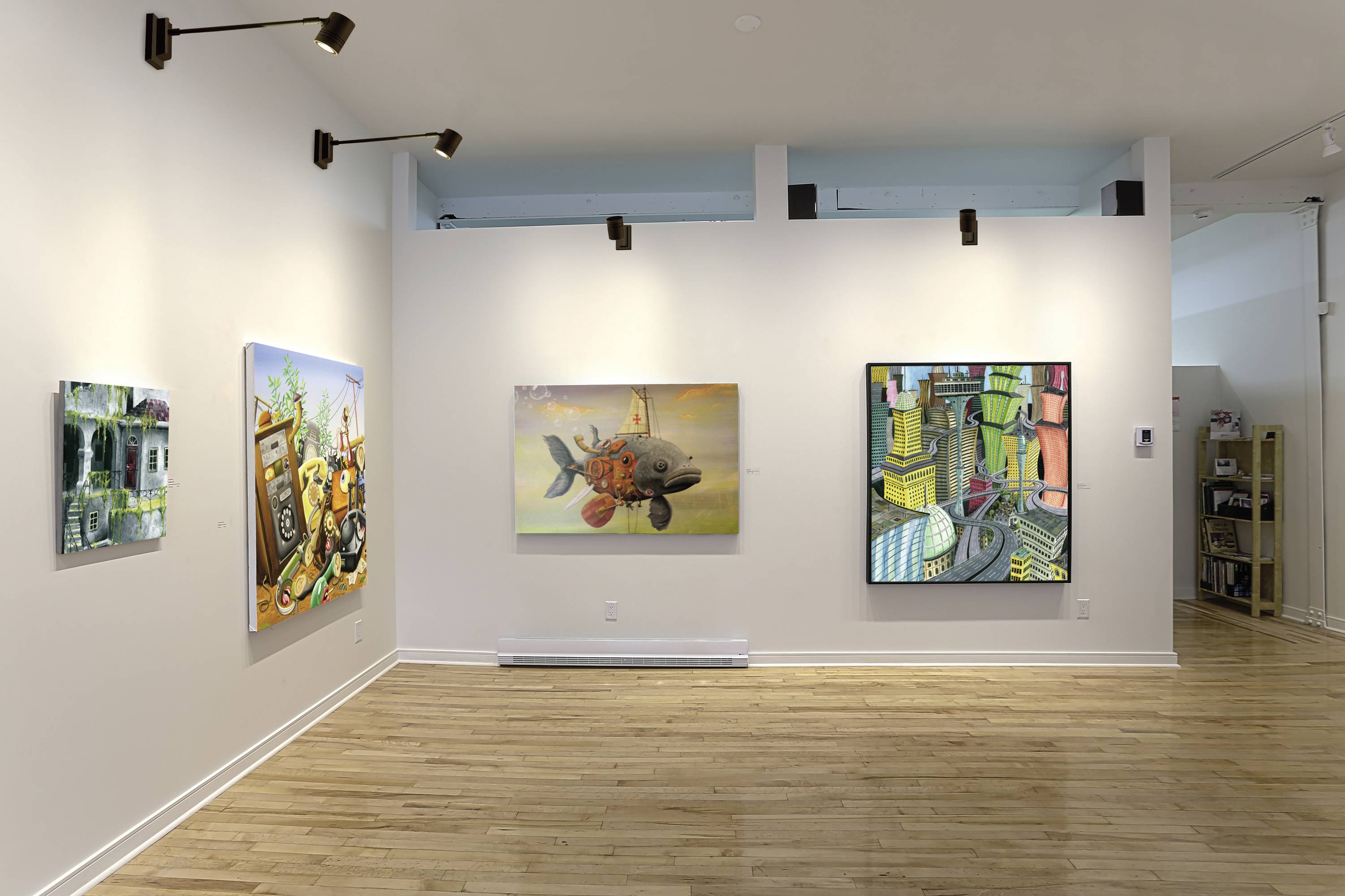 Ein Raum in einer Kunstgalerie mit vier modernen Gemälden an weißen Wänden, hellem Holzboden und schlichter Deckenbeleuchtung.