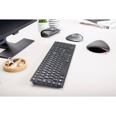 Arbeitsplatz mit schwarzer Tastatur und Maus auf einem Schreibtisch. Weitere Gegenstände sind Stifthalter, Monitor und Notizbücher.