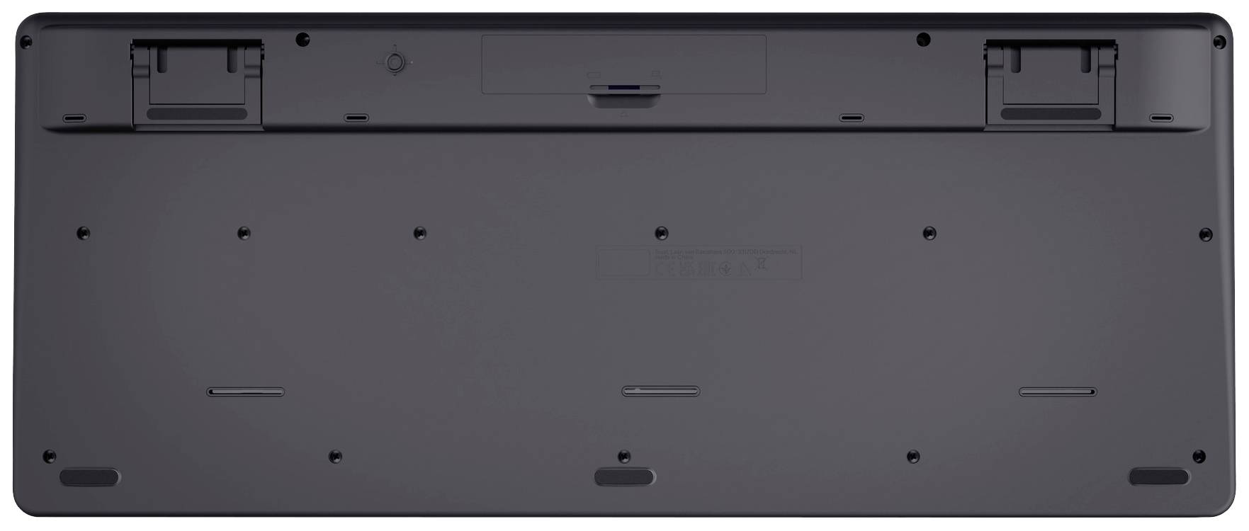 Die Rückseite einer schwarzen Computer-Tastatur mit sichtbaren Batteriefachabdeckungen und rutschfesten Noppen an den Ecken.