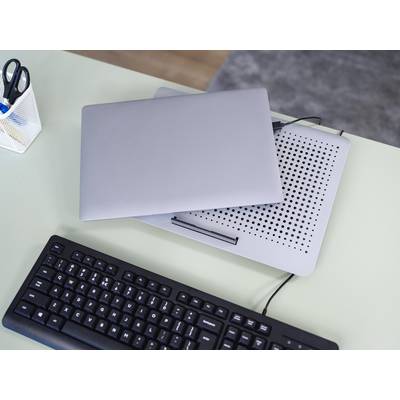 Geschlossener Laptop auf einem Kühlpad auf einem Schreibtisch mit Tastatur. Im Hintergrund steht ein Stifthalter.