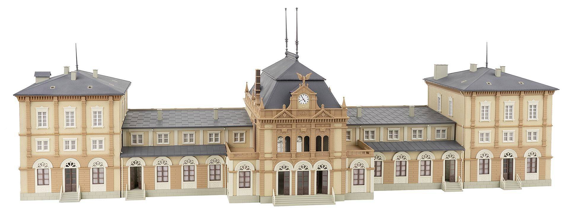 Ein Modell eines historischen Bahnhofs mit zwei Seitentürmen und einem mittigen Uhrturm. Verzierungen und Fenster betonen die Architektur.