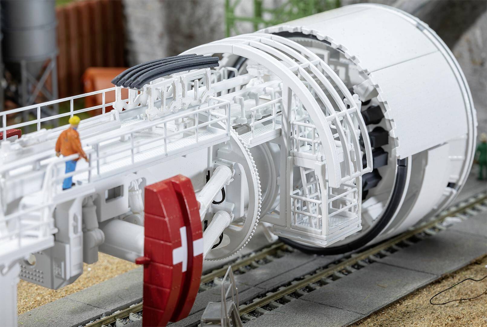 Tunnelbohrmaschine mit rotierendem Bohrkopf, im Einsatz auf einer Baustelle. Eine Person im Schutzhelm steht daneben, Überwachung der Arbeiten.
