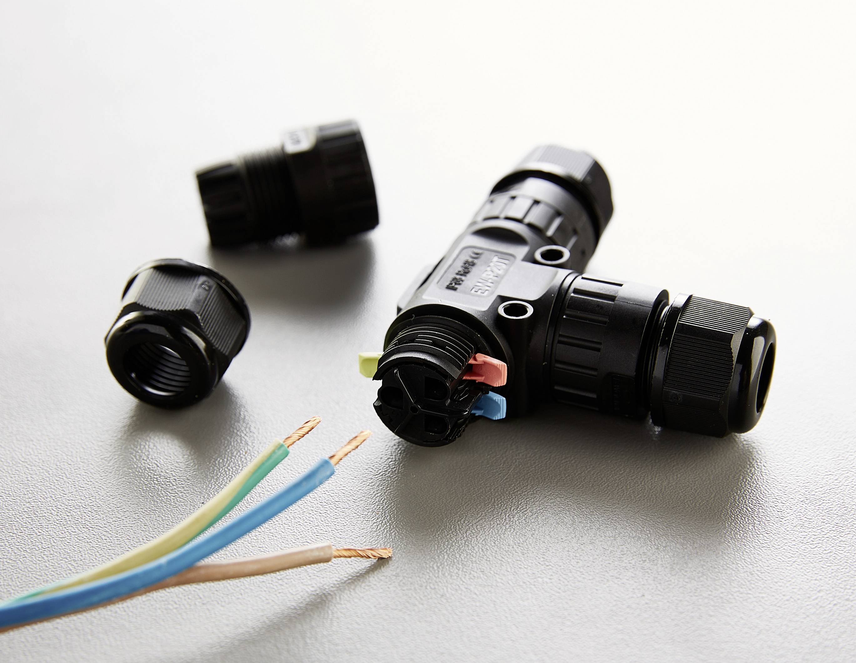 Ein Y-Steckverbinder mit offener Isolierung, drei auseinandergebaute Anschlussstücke und freiliegende Kabelenden auf grauem Hintergrund.