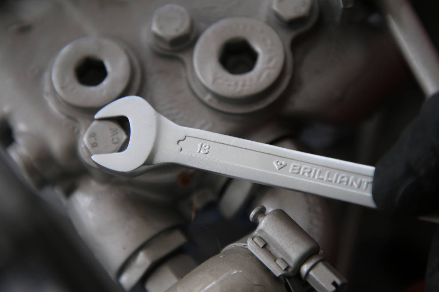 Ein Schraubenschlüssel greift an eine sechseckige Mutter in einem mechanischen Bauteil.