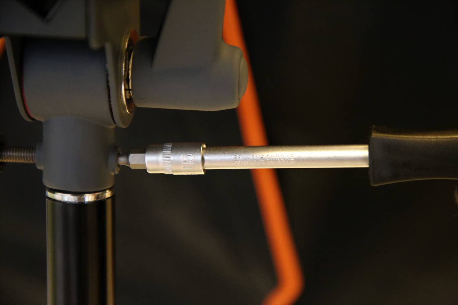 'Nahaufnahme eines Stativs mit grauen und schwarzen Komponenten, Fokus auf die Befestigung und Einstellmechanismus.'