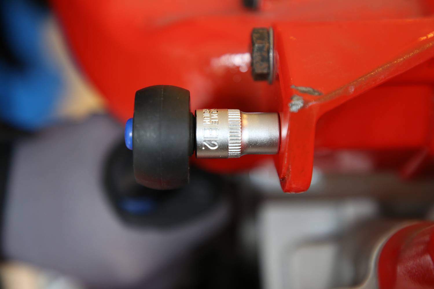 Ein rotes mechanisches Gerät mit einem schwarzen und silbernen einstellbaren Teil, möglicherweise Teil einer Maschine oder Ausrüstung.