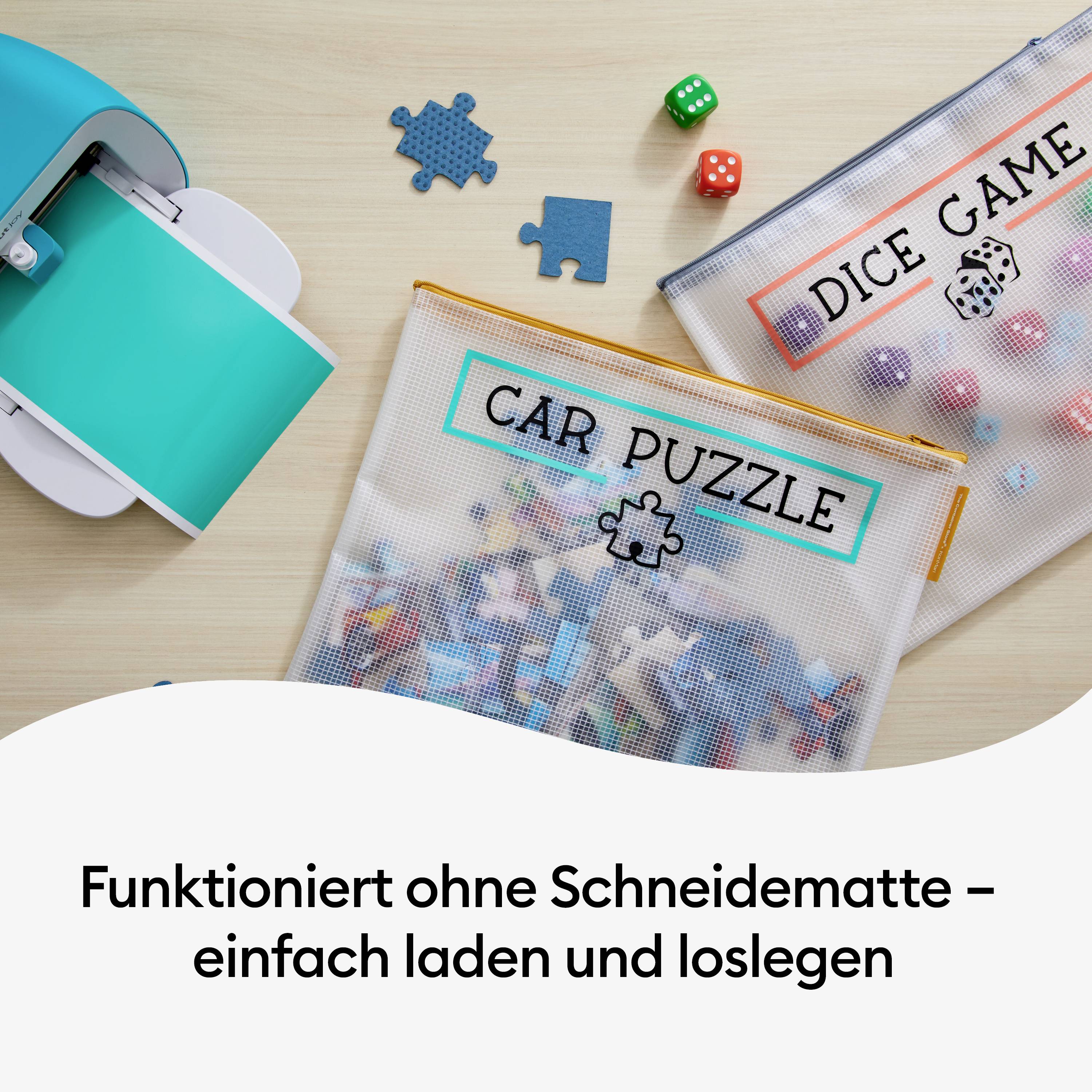 Ein Tisch mit einem Drucker, Spielzeugsäckchen beschriftet mit 'CAR PUZZLE' und 'DICE GAME', und der Text 'Funktioniert ohne Schneidematte – einfach laden und loslegen'.