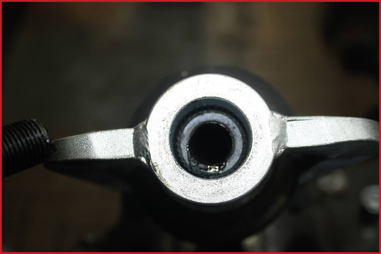 Nahaufnahme einer Metallstruktur mit zentralem kreisförmigem Loch und seitlichen Hebeln, möglicherweise Teil eines mechanischen Geräts.