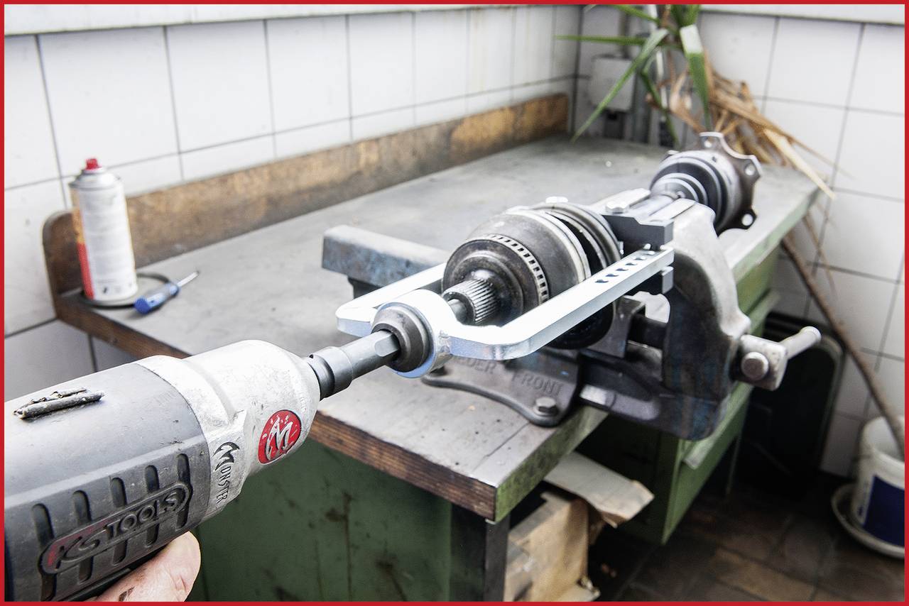 Eine Person repariert ein mechanisches Teil auf einer Werkbank mit einem elektrischen Drehwerkzeug und einer Schraubzwinge.