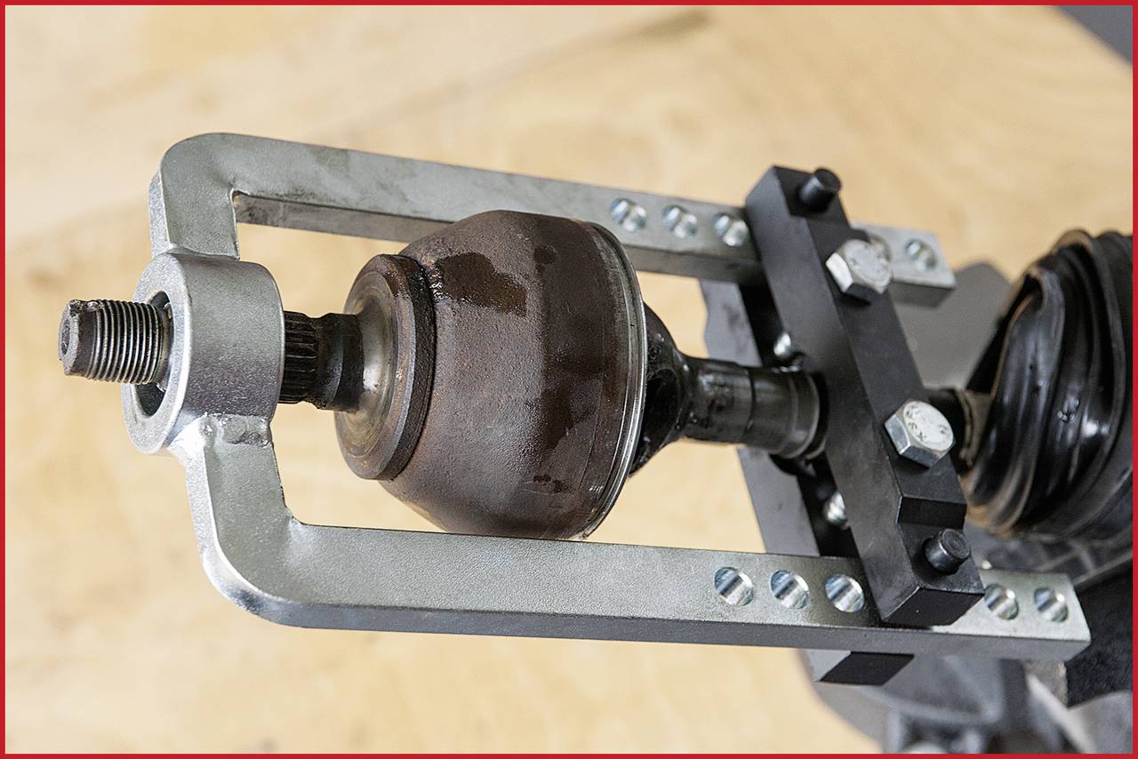 Eine Nahaufnahme eines Achsgelenks, das in einer Metallvorrichtung befestigt ist, vermutlich in einer mechanischen Werkstatt.