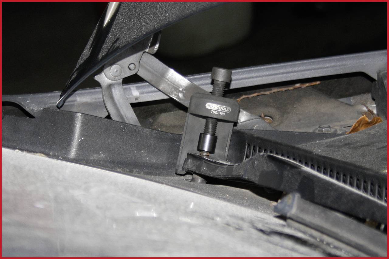 Ein Abzieher-Werkzeug wird auf einer Autowindschutzscheibe verwendet, um den Wischerarm zu entfernen.