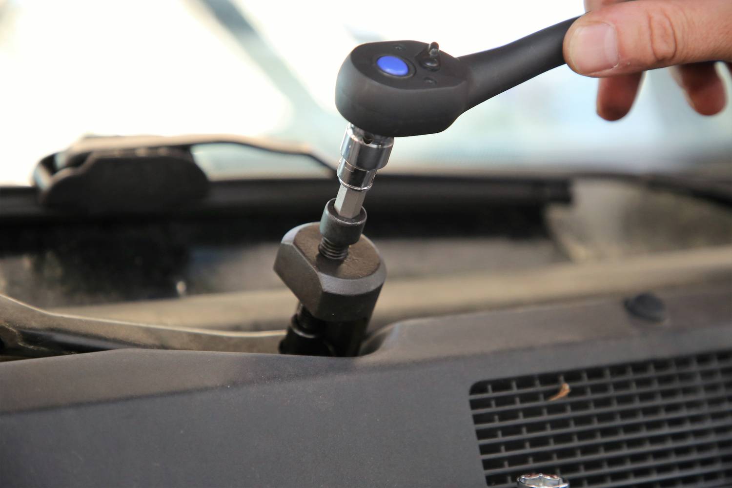 Eine Hand benutzt einen Schraubenschlüssel, um eine Schraube an einem Auto zu befestigen oder zu lösen.