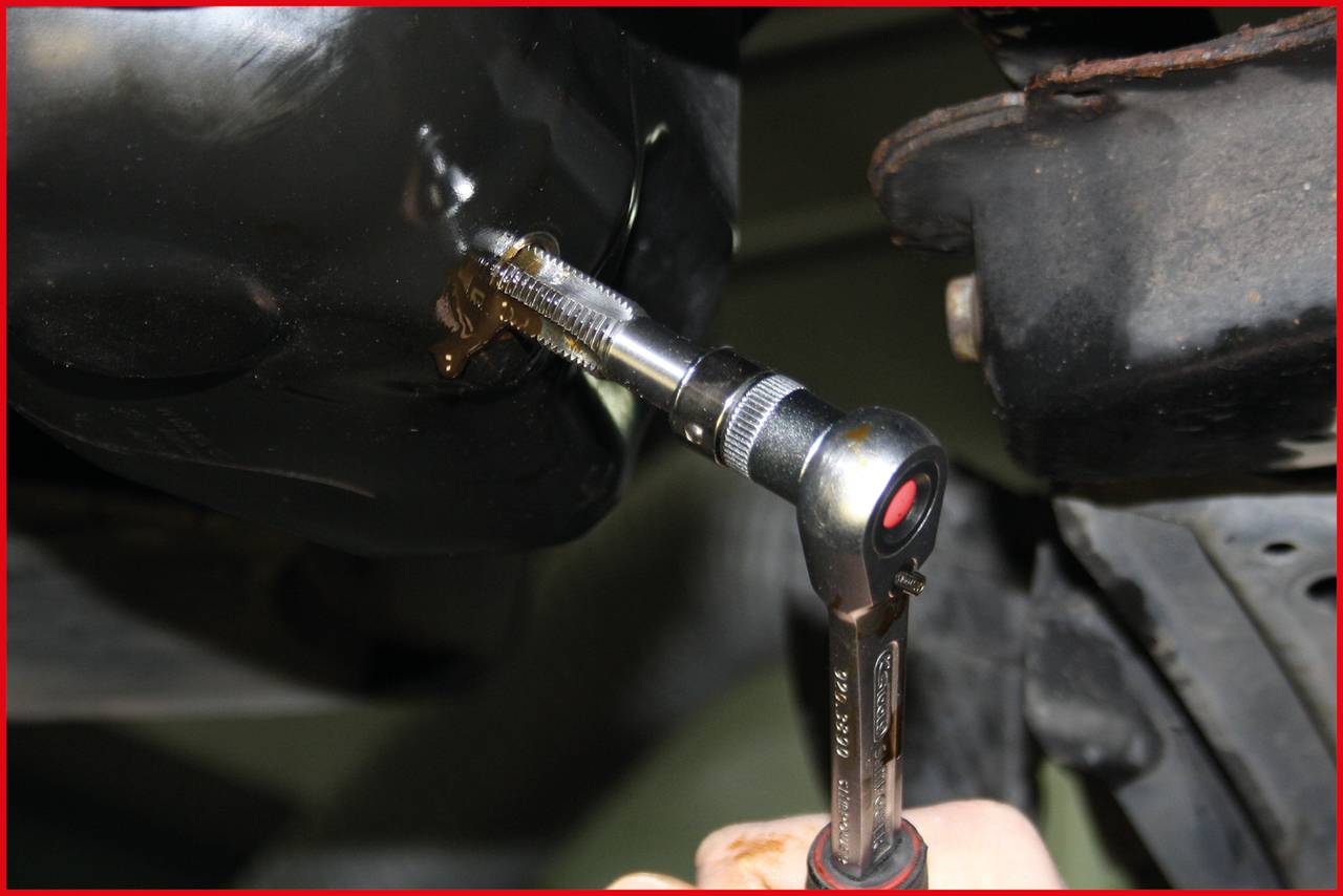 'Nahaufnahme einer Ratsche, die einen Schraubenkopf an einem Metallgehäuse dreht. Mechanische Arbeit an einem Fahrzeug.'