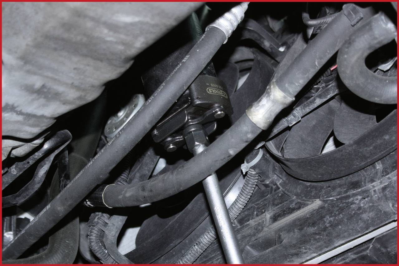 Einblick in einen Automotorraum mit verschiedenen Schläuchen und Kabeln, die über und um einen zentralen Mechanismus verlaufen.