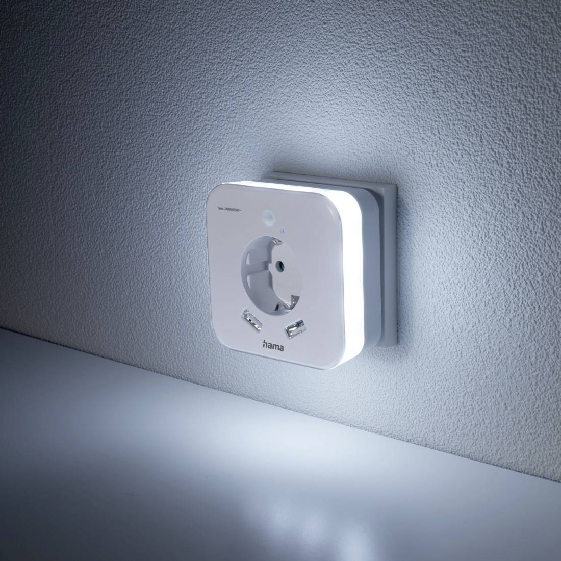 Ein Nachtlicht in Form einer Steckdose mit integriertem Bewegungsmelder leuchtet an einer Wand und bietet sanfte Beleuchtung.