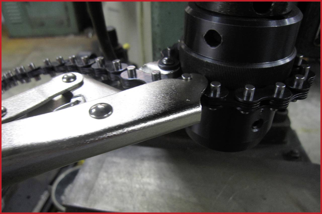 Metallmaschine mit Kette und Hebel, die in einer Werkstatt auf einem Tisch montiert ist. Detailaufnahme der Mechanik.