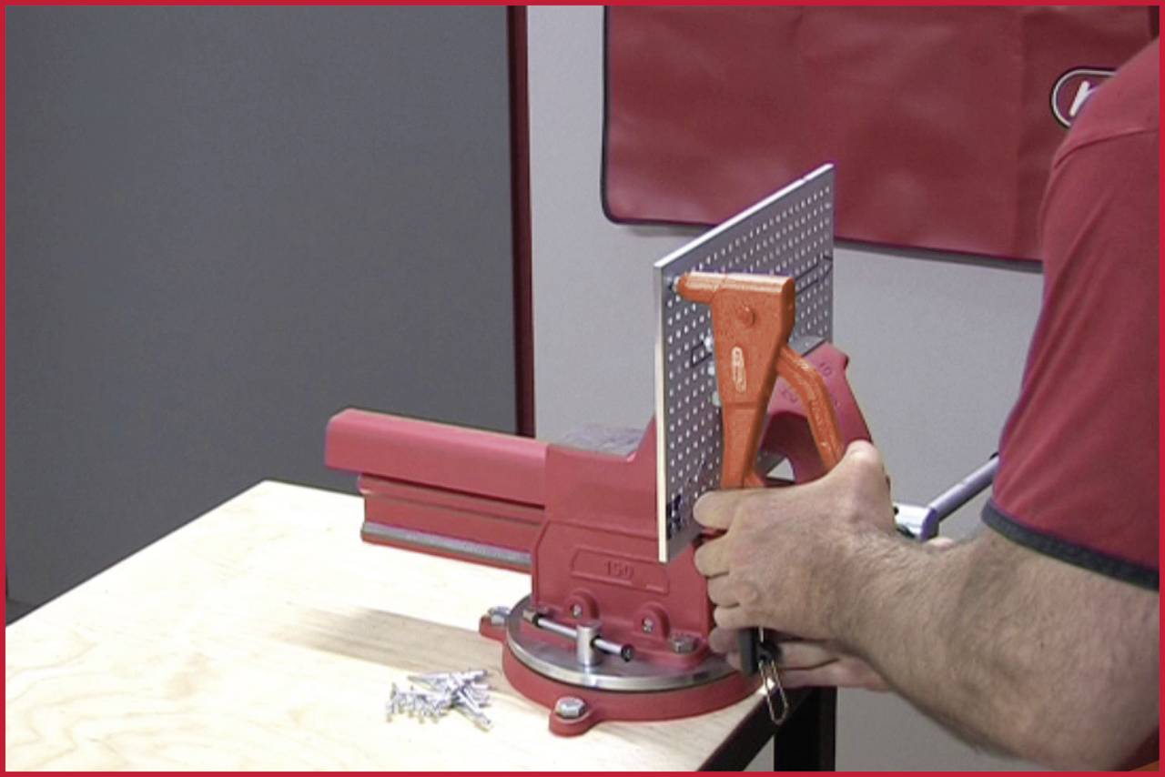 Eine Person zieht einen Biegenhebel, um ein Blech mit Hilfe einer Eckeinspannvorrichtung zu biegen. Im Vordergrund liegen Schrauben.