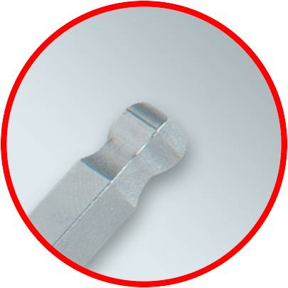 Nahaufnahme eines stumpfen Metallschrankschlüssels, silberfarben, mit einem runden Profil vor grauem Hintergrund.