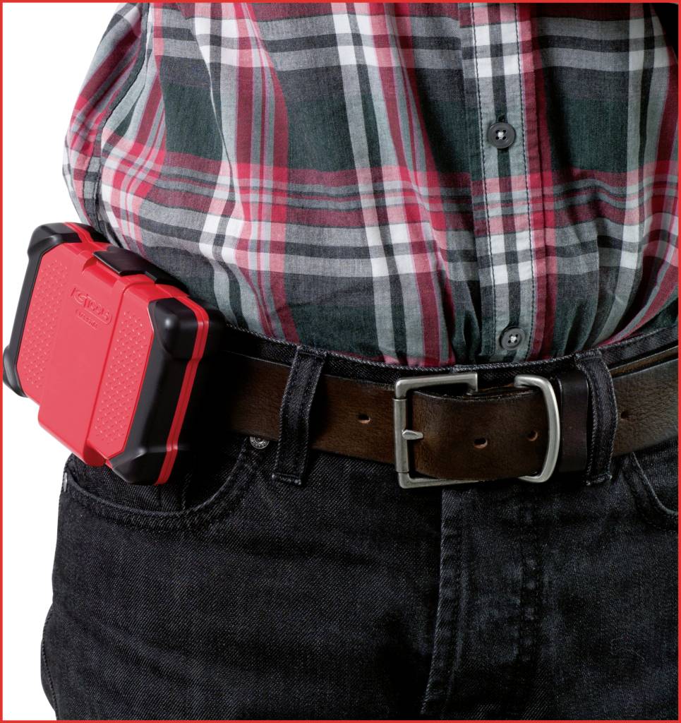 Eine Person trägt ein kariertes Hemd und einen braunen Gürtel mit einer roten Werkzeugbox am Gürtel befestigt.