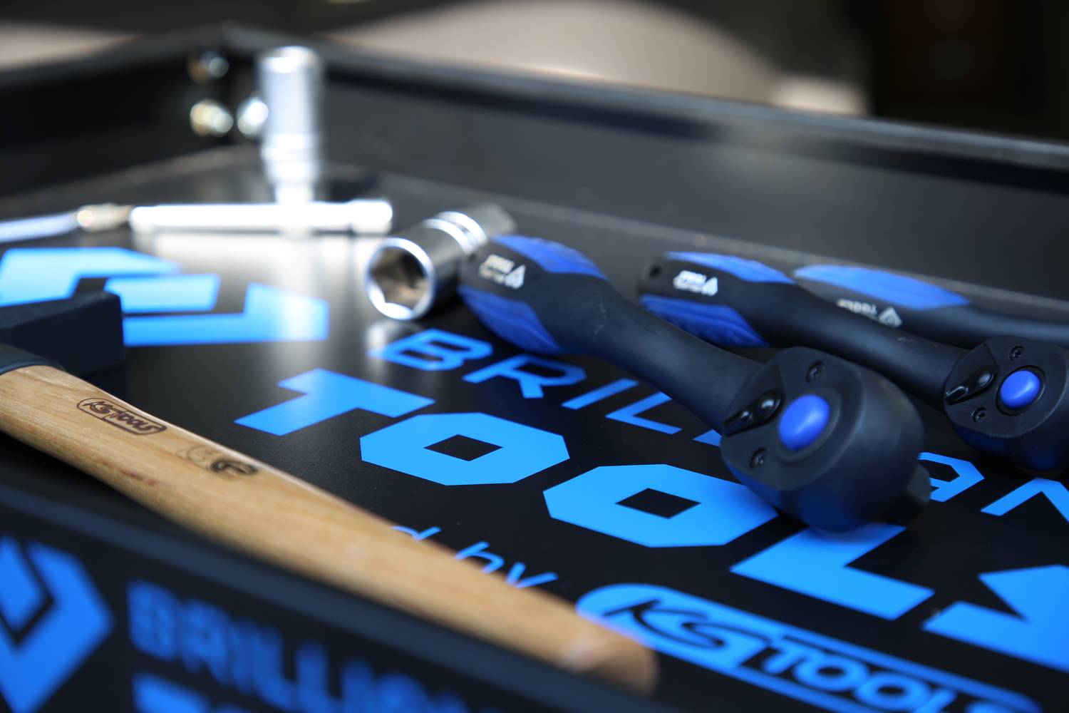 Werkzeugkoffer mit verschiedenen Werkzeugen wie Hammer, Schraubendreher und Steckschlüsseln; Firmenlogo sichtbar.